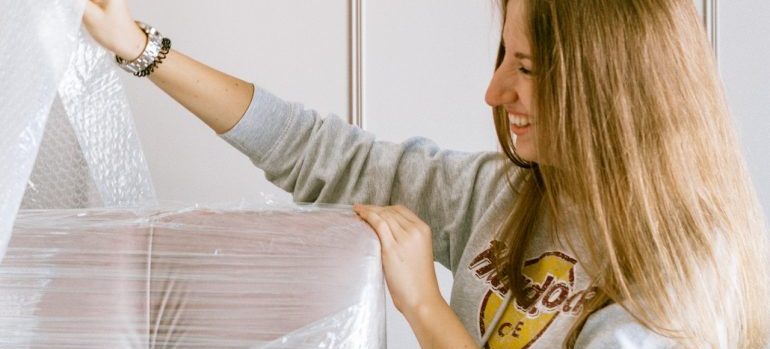 woman protecting furniture with plastic wrap 