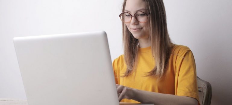 a woman in a yellow blouse writing a review on her laptop