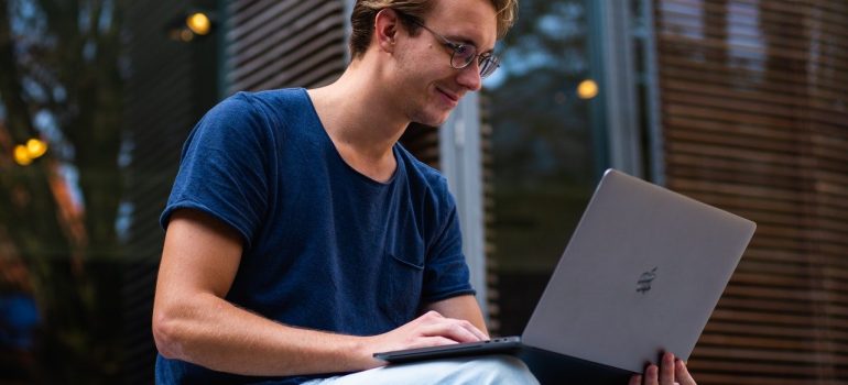 a man in a blue shirt smiling while looking at his laptop