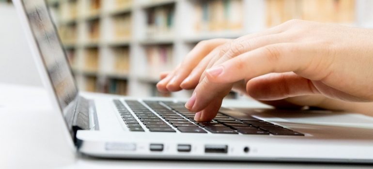 a person typing on their laptop as the best way for rating your Brockville movers 