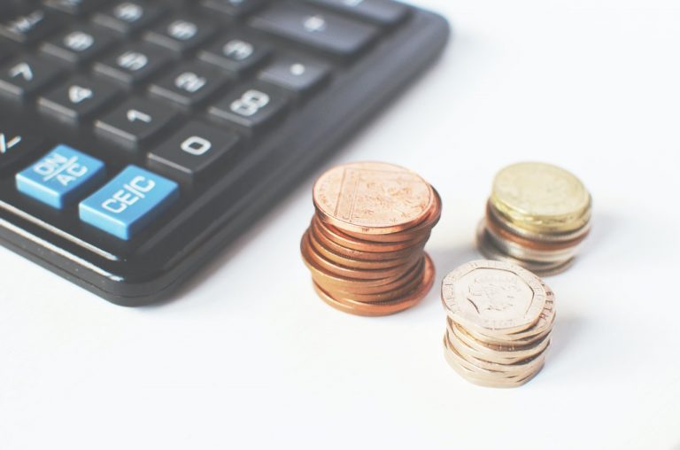 a calculator on the table next to three small stacks of coins