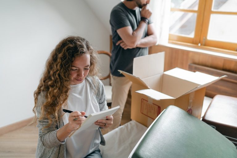 a woman creating a checklist while a man is thinking behind her