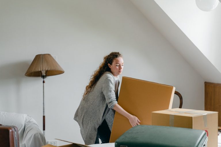 a woman lifing a larger cardboard box in her living room