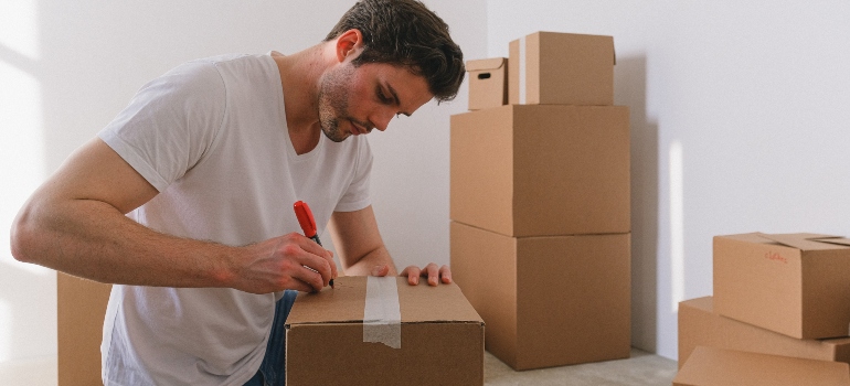 man writing on the moving boxes
