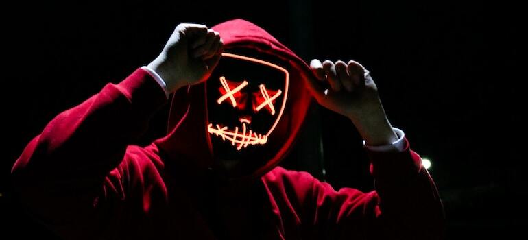 A person wearing a red hoody and a spooky maks