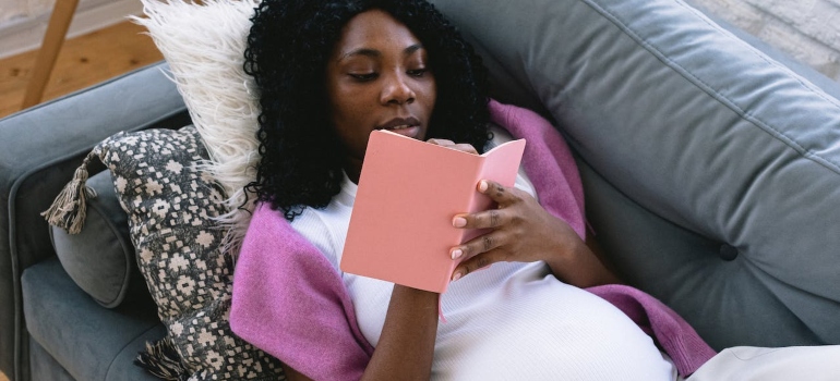 a woman lying down and reading about moving while pregnant