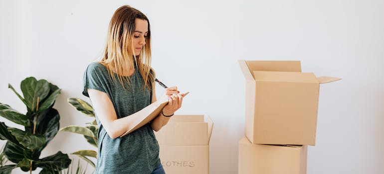 A woman packing boxes and following the room by room packing guide