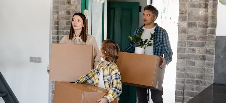 Parents and their child carrying boxes