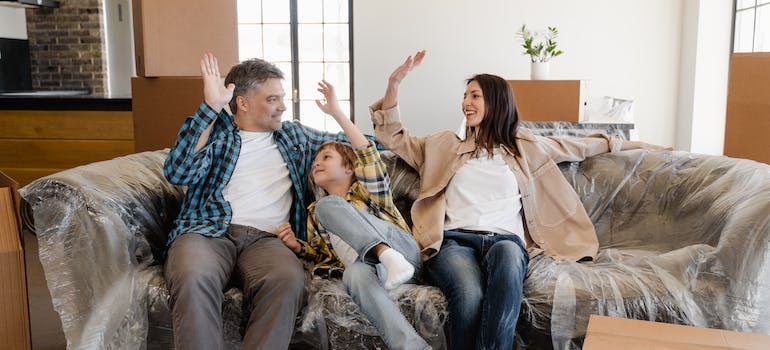 A family sitting on a couch covered in plastic wrap