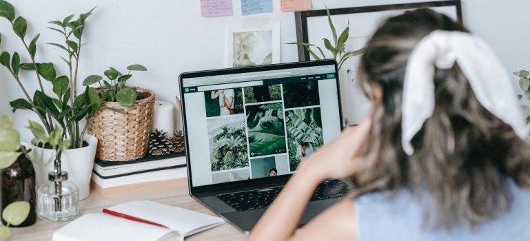 Woman at her desk looking up photos on her laptop