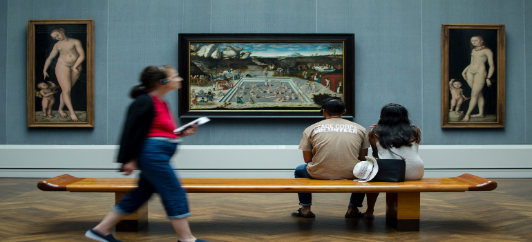 A couple sitting on a bench and looking at paintings
