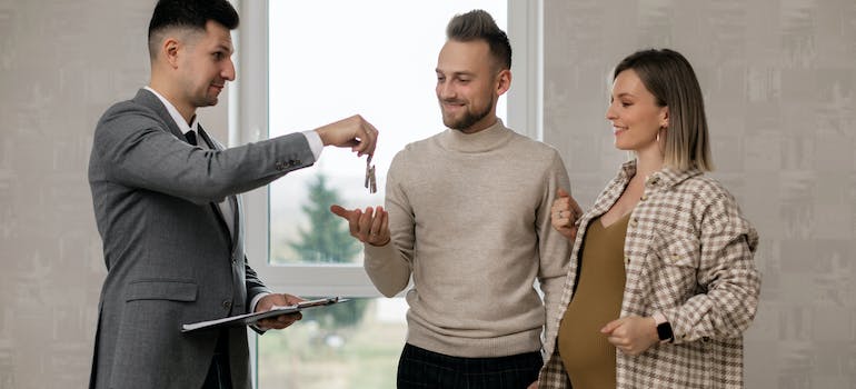 A real estate agent handing key to a couple