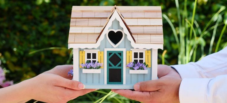Hands holding a small wooden house