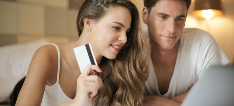 a woman holding a card and a man reading on a laptop about renting vs. owning in Ottawa in 2024