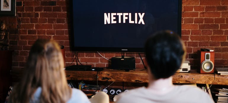 a man and a woman sitting and watching Netflix on TV