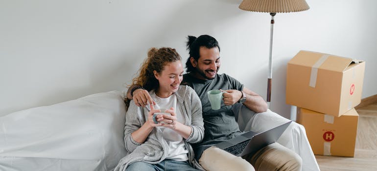 A couple sitting on a couch looking at a laptop