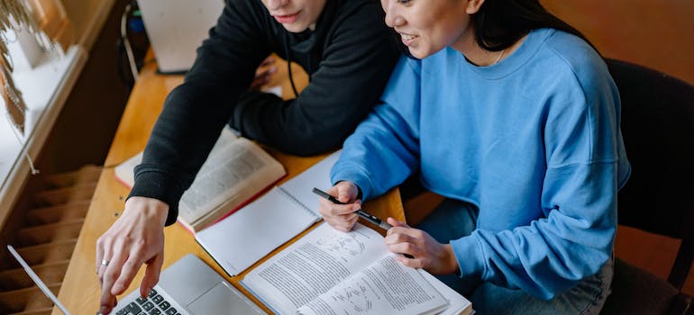 a young woman and a man reading on a laptop