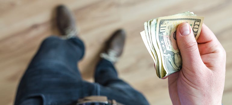 Man Holds money in his hand, costs of moving to Ottawa in 2024 can be really high