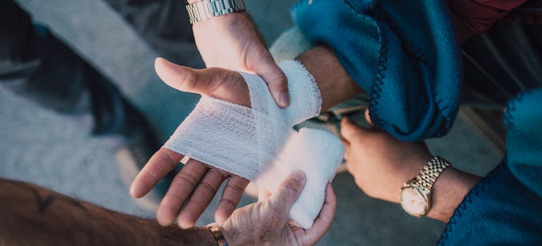 Person applying bandage on other person's hand.