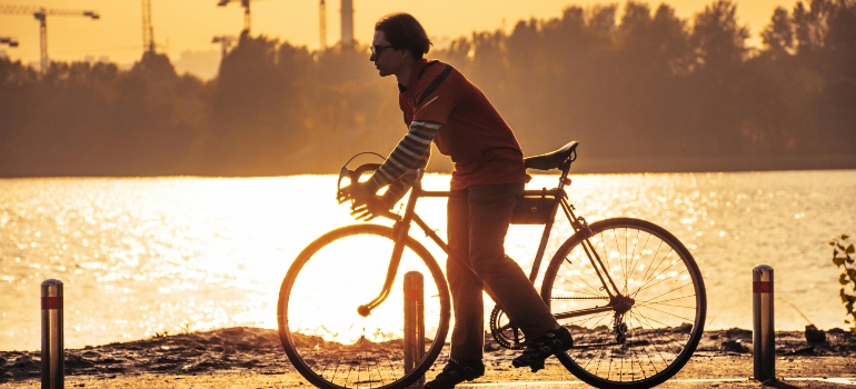 Man Cycling along River at Golden Hour