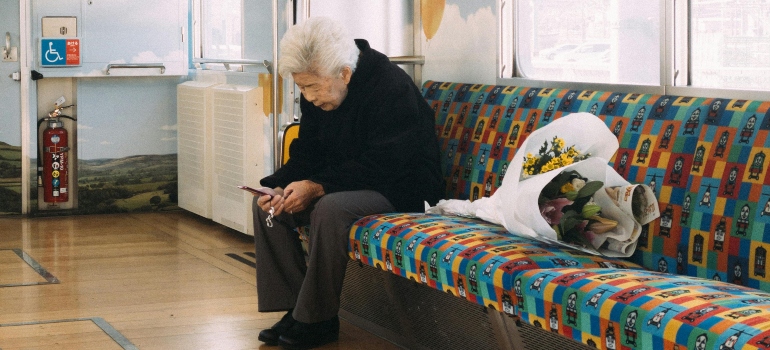 Old Asian man using smartphone while riding in subway