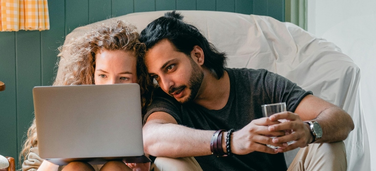 Positive couple using laptop after moving in together in Ottawa