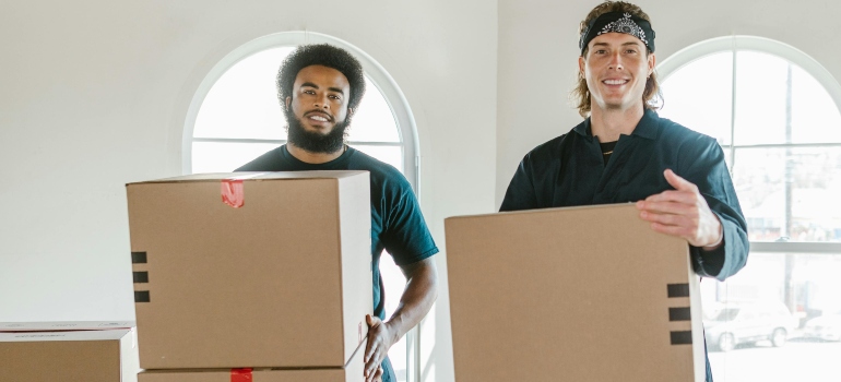 Two Men Standing Carrying Cardboard Boxes