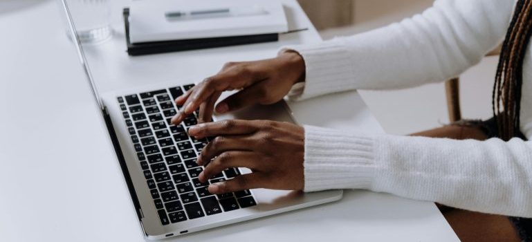 Hands typing on laptop keyboard and trying to spot fake online moving reviews