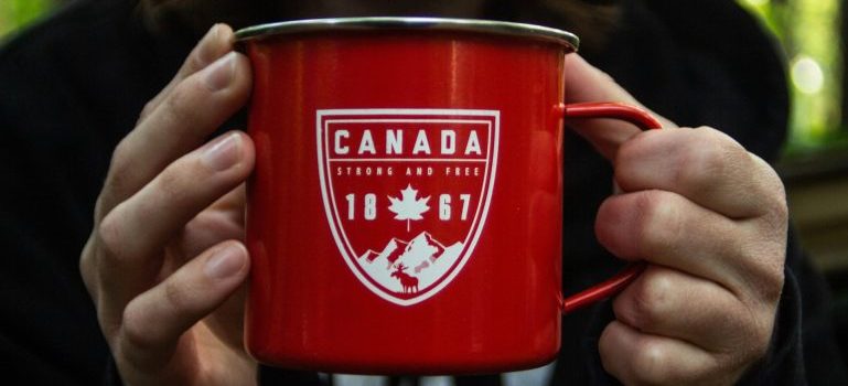 Hands holding a red mug with Canadian motives on it