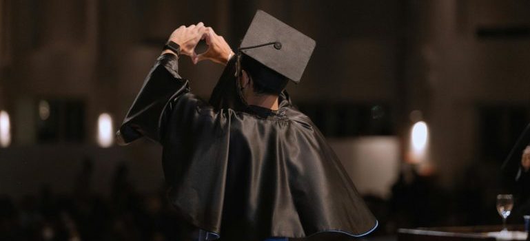 Graduate in a gawn holding up a heart sign after moving for the quality of life in the Ottawa area