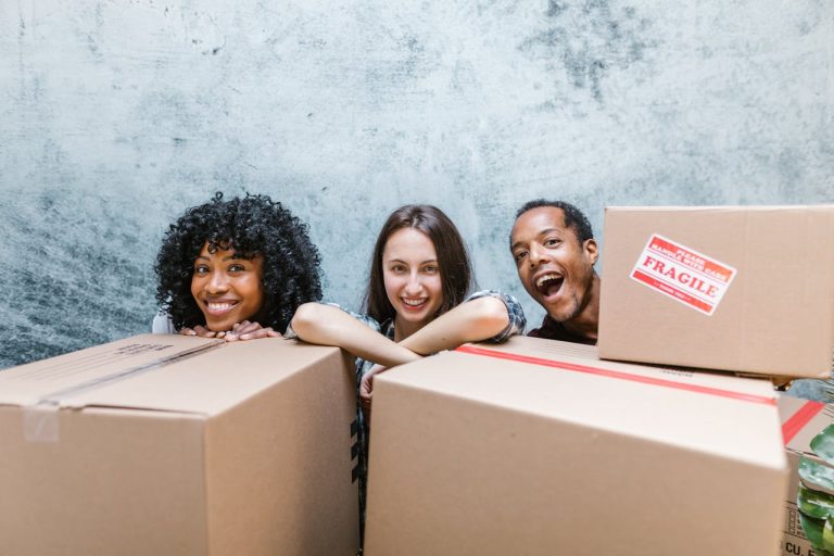 a man and two women standing behind boxes discussing how to help a friend move