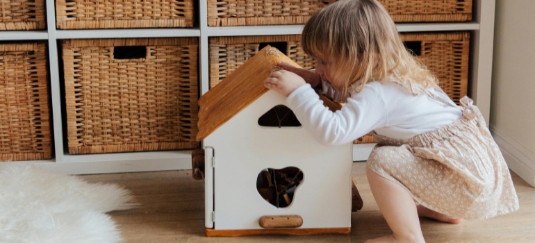 Girl Playing With A Wooden Toy House