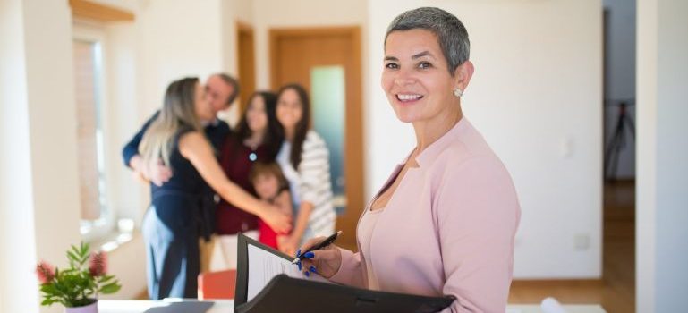 real estate agent holding papers and family hugging 