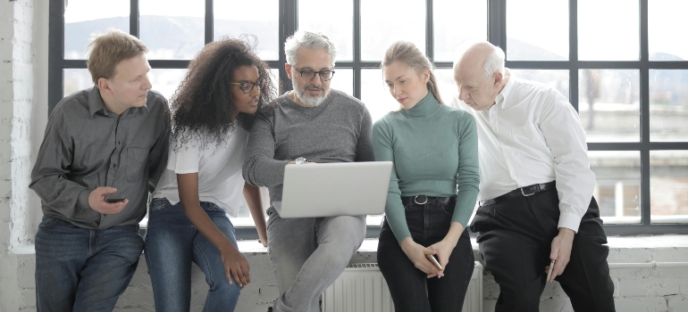A group of people in the office looking at a laptop.