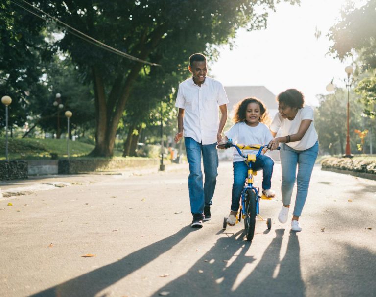 parents showing a child how to ride a bike