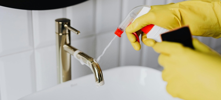 Faceless cleaner in gloves tiding up bathroom