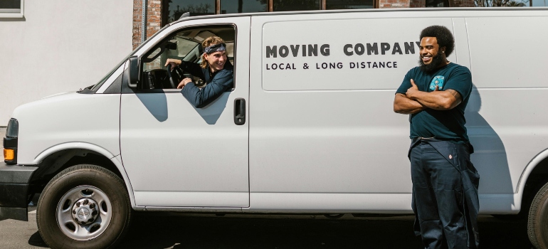 Man in Blue Long Sleeve Shirt and Blue Denim Jeans Standing Beside White Van