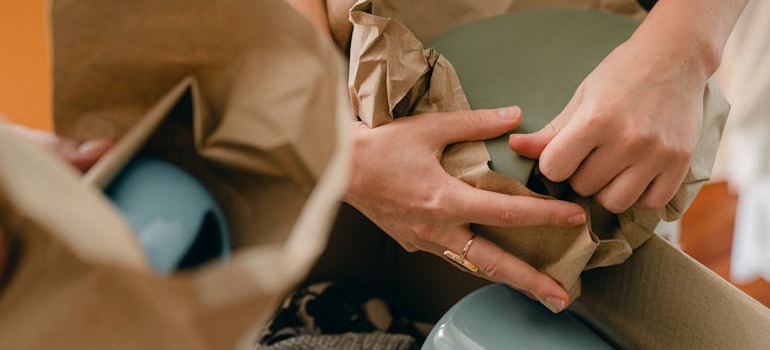 Two people packing blue vases