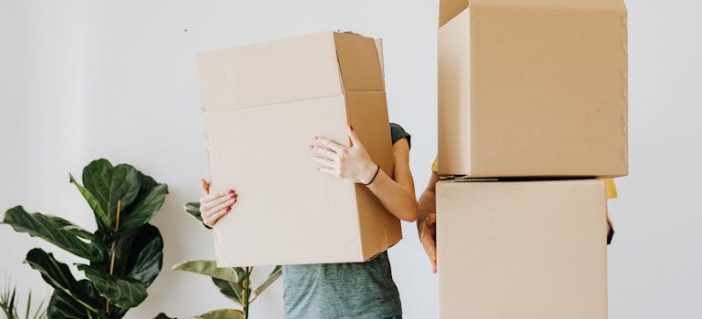 Two people holding moving boxes