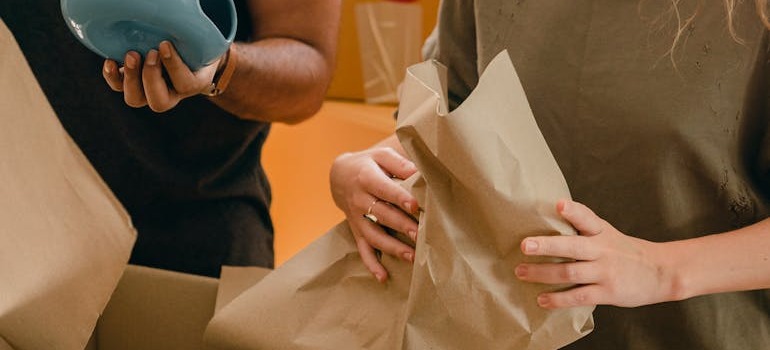 A couple wrapping up their vases in packing paper and discussing dos and don’ts of packing a storage unit