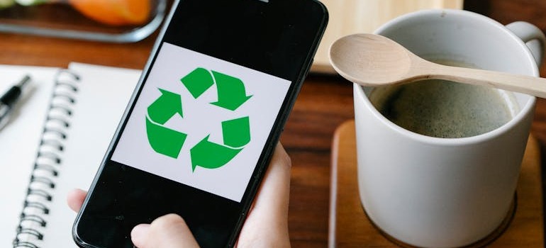 A person holding a smartphone with the recycle emblem on it