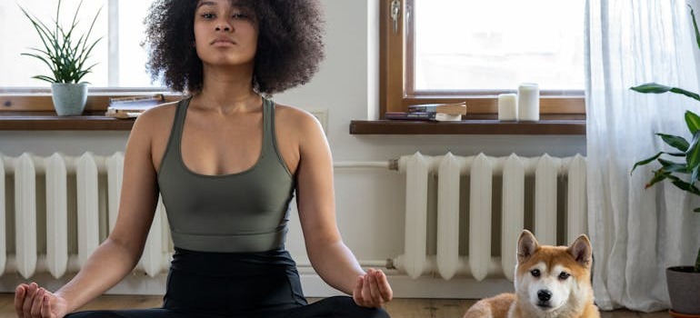 A woman doing yoga beside her dog