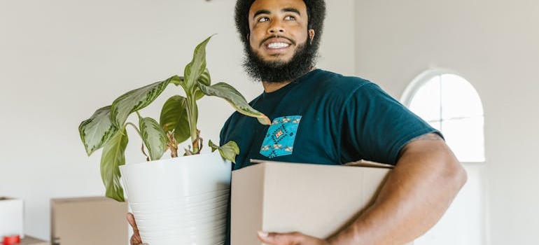 A person holding a moving box and a vase