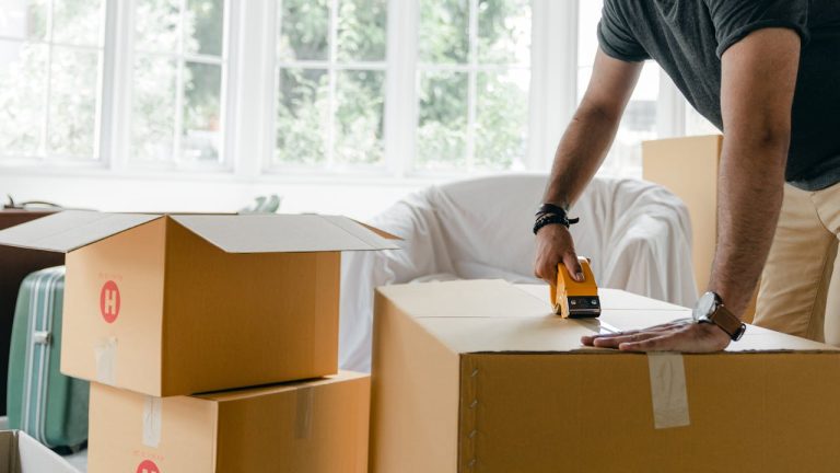 A person closing a box before putting it into temporary storage solutions in Ottawa