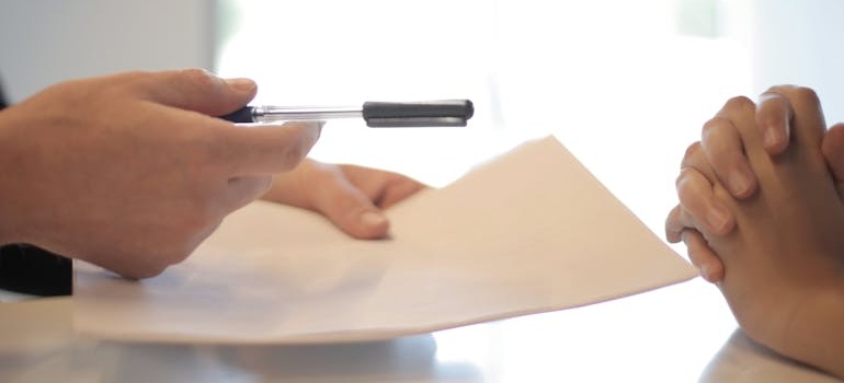 A person giving another person documents and a pen