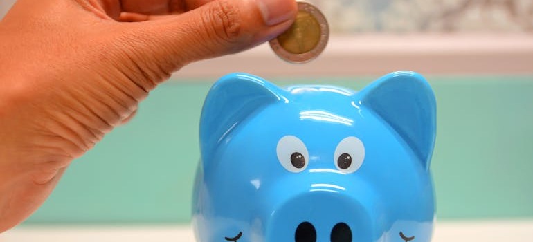 A person putting money inside a blue piggy bank