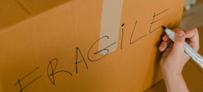 A person putting a fragile label on a moving box