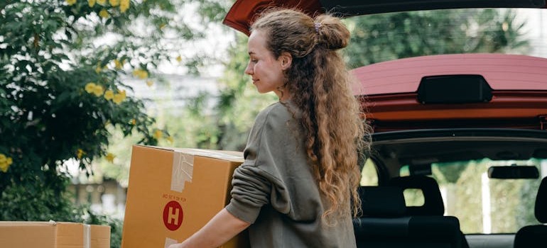 A woman taking a moving box from her car
