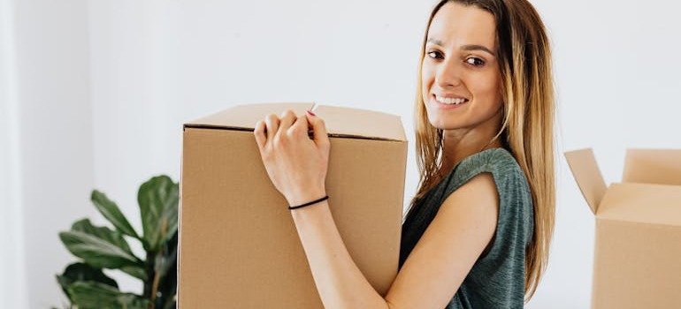 A young person holding a moving box