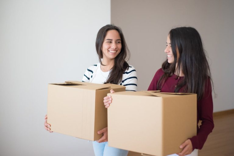 Two girls carying boxes and using the moving tips for college students in Canada